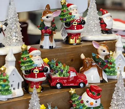 A store display of various Christmas & holiday items: Santa Claus figurines, reindeer, trees, & more